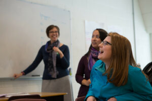 Teacher looks at two excited students staring at the whiteboard