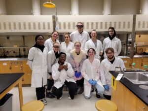 Several chemistry students and their professor pose in a lab